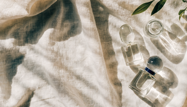 Fresh perfume bottles on linen in daylight